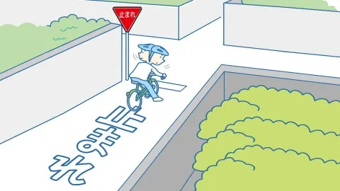 「止まれ」の標識がある交差点で、一時停止して左右を確認している自転車に乗っている人