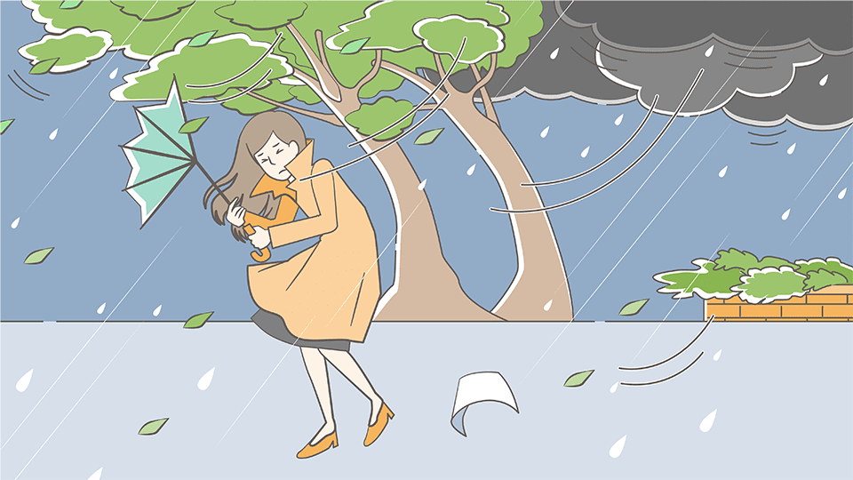 暴風雨の中を傘をさして歩く女性。強風で木の枝がなびき、傘が飛ばされそうになっている。