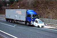高速道路上で乗用車が後続のトラックに追突された事故の写真