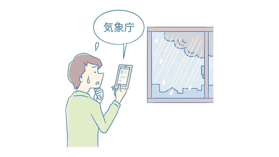 大雨の日に、スマートフォンを使って「洪水キキクル」で危険度を確認している男性